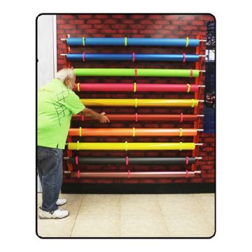 A colorful display of rolls on a "Mondo Raxx Jumbo Mountable Media Roll Storage" system mounted against a brick wall.