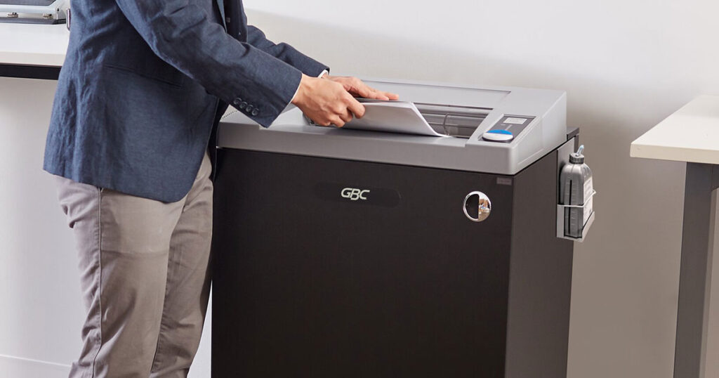 Government employee using a GBC shredding machine to destroy paper.
