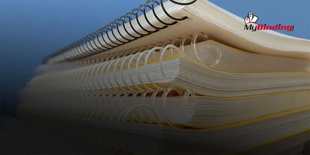 Stack of coil-bound booklets showcasing different colored spiral coils.