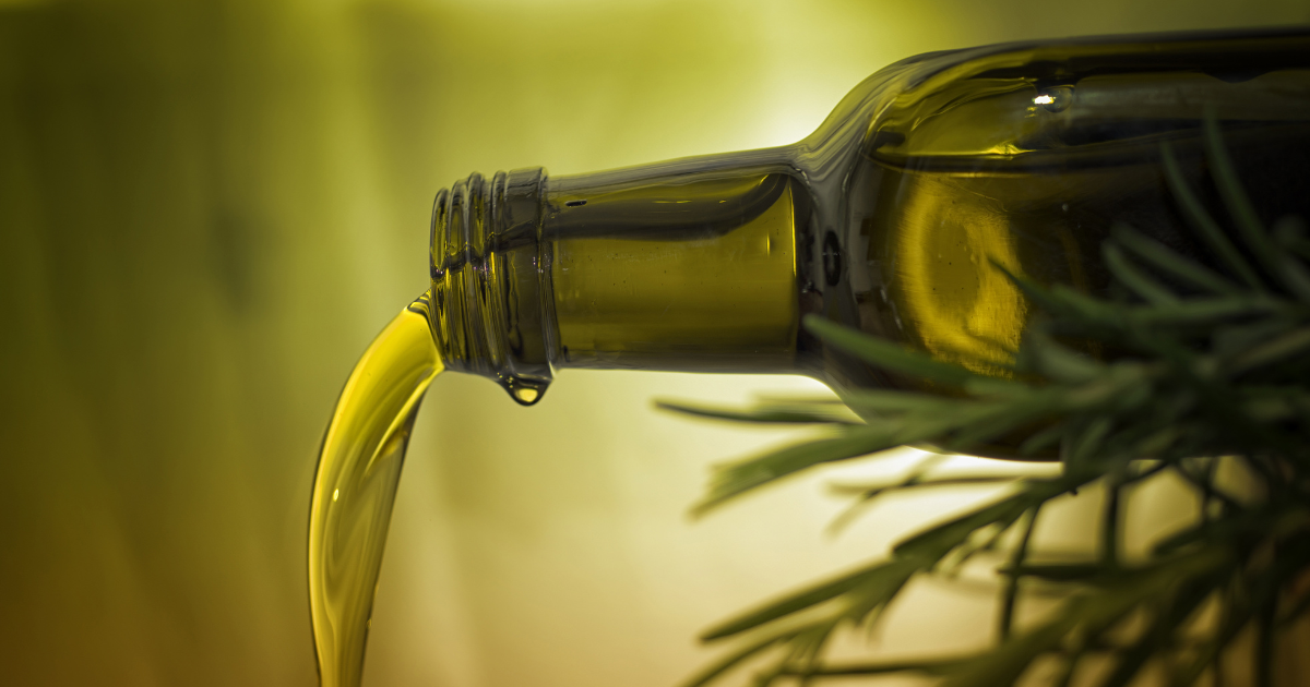 Oil pouring out of its bottle in a graceful stream.