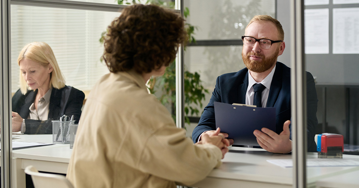 Employees sitting at a desk reviewing a clipboard.