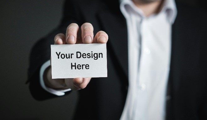 Man in a suit holding out a business card with 'your design here'