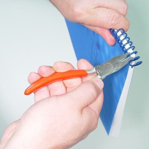 MyBinding employee using crimpers on the spiral coils of a blue notebook