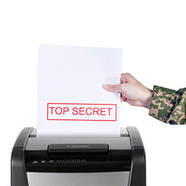 A person in military camouflage uniform feeds a sheet labeled "TOP SECRET" into a paper shredder, representing secure document disposal as part of Military Office Supplies.
